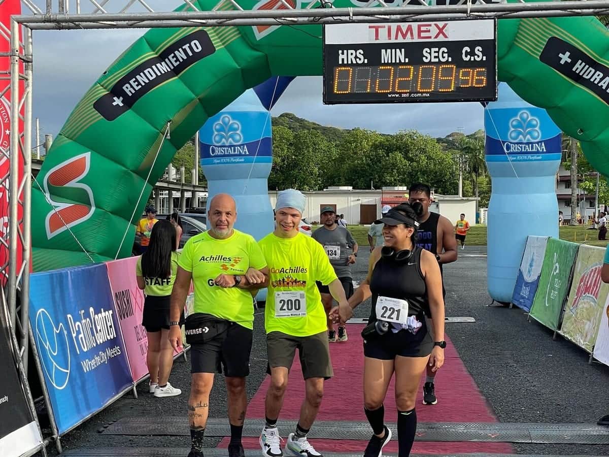 Un atleta llega a la meta acompañado por sus dos guías